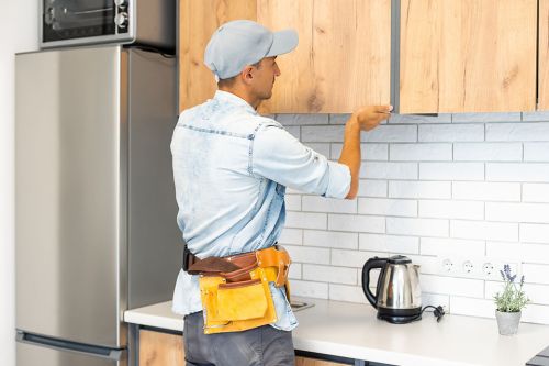 © Angelov - stock.adobe.com Foto: Handwerker baut Küchenschrank ein